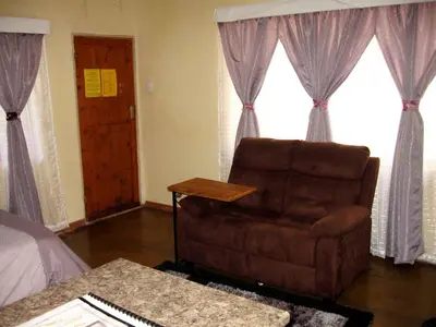 a living room with a chair and a bed at The Shoe Guest House in Draasloot