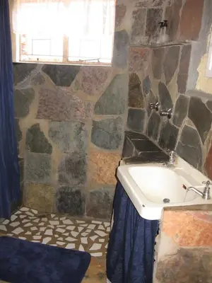 a stone bathroom with a sink and a tub at The Shoe Guest House in Draasloot