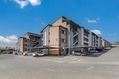 a parking lot with cars parked in front of a building at Resting nest waterfall in Midrand