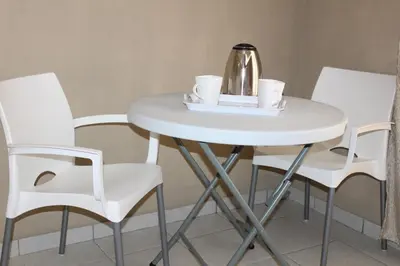 a white table with white chairs and a tea kettle at Unit G Guest House in Ga-Mothiba