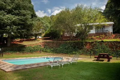 a pool with chairs and a table next to a house at Viewpoint Estate Accommodation in Haenertsburg