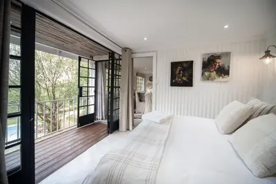 a bedroom with a white bed and a large window at Viewpoint Estate Accommodation in Haenertsburg