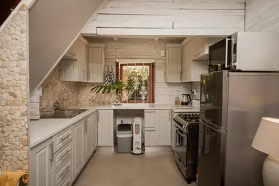 a kitchen with white cabinets and a stainless steel refrigerator at Viewpoint Estate Accommodation in Haenertsburg