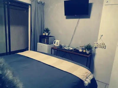 a bedroom with a bed and a table with a microwave at Be Our Guest Near OR TAMBO International Airport in Boksburg