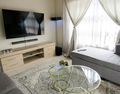 a living room with a tv and a bed and a table at Khaya Guesthouse in Soshanguve