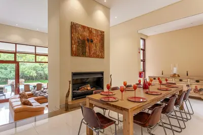 a dining room with a table and a fireplace at Lejwe La Metsi Self-Catering Villa in Bela-Bela