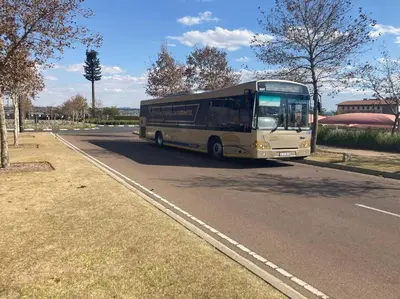 a bus is driving down a road at Luxury Apartment at Ellipse Waterfall, Midrand Near Mall of Africa in Midrand