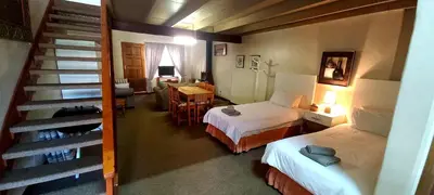 a hotel room with two beds and a staircase at Villa Moria Memoir Cottage in Dullstroom