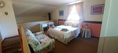 a bedroom with a bed and a chair and a window at Villa Moria Memoir Cottage in Dullstroom