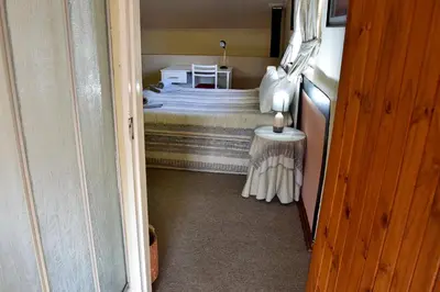 a small bedroom with a bed and a small table at Villa Moria Memoir Cottage in Dullstroom