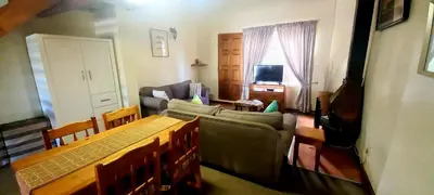 a living room with a couch and a table and chairs at Villa Moria Memoir Cottage in Dullstroom