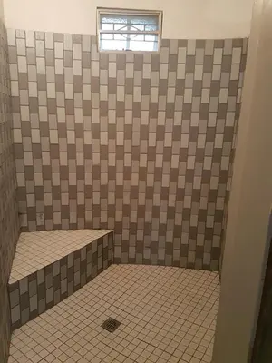 a bathroom with a tiled shower with a window at Kiaat Bungalows in Hazyview