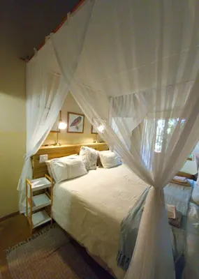 a bedroom with a canopy bed with white curtains at Kiaat Bungalows in Hazyview
