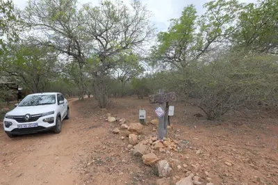 a white car parked next to a sign on a dirt road at Oasis in the Wild @Marloth in Marloth Park