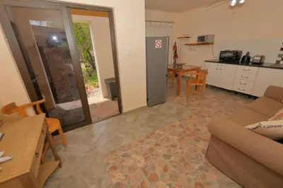 a living room with a couch and a table and a kitchen at Oasis in the Wild @Marloth in Marloth Park