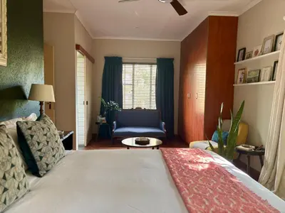 a bedroom with a bed and a chair and a window at Fig Tree Rock 2-bed, 2-bath villa with garden and parking in Nelspruit