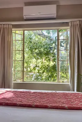 a bedroom with a large window with a red rug at Fig Tree Rock 2-bed, 2-bath villa with garden and parking in Nelspruit