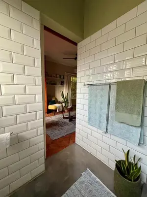 a room with a white brick wall with a window at Fig Tree Rock 2-bed, 2-bath villa with garden and parking in Nelspruit