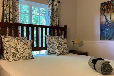 a bedroom with a bed with pillows and a window at Elm Tree House - Dullstroom - holiday home in Dullstroom
