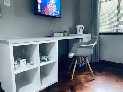 a white desk with a chair and a television on a wall at 46 on Allcock Guest Apartment & Luxury Room in Pretoria
