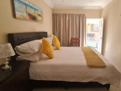 a bedroom with a bed with yellow pillows and a window at Benoni N12 Hotel in Benoni