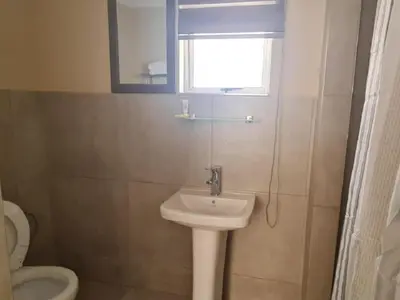 a bathroom with a sink and a toilet and a window at Benoni N12 Hotel in Benoni