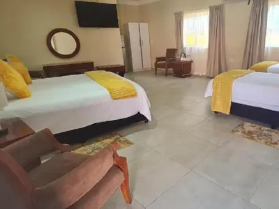 a hotel room with two beds and a chair at Benoni N12 Hotel in Benoni