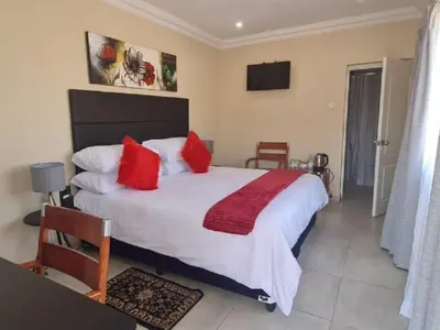 a bedroom with a large bed with red pillows at Benoni N12 Hotel in Benoni