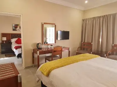 a hotel room with a bed and a desk and a bedroom at Benoni N12 Hotel in Benoni