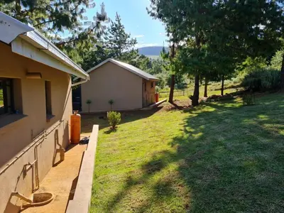 a backyard of a house with a grass yard at Ukutula Resort in Dullstroom