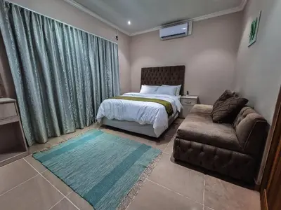 a bedroom with a bed and a couch and a chair at Bela Valley Guest House in Bela-Bela
