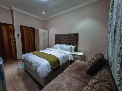 a bedroom with a large bed and a couch at Bela Valley Guest House in Bela-Bela