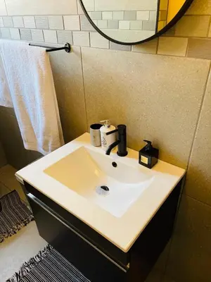 a bathroom with a white sink and a mirror at Luxuries Penthouse in Nelspruit