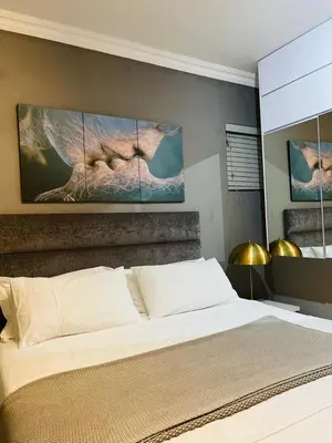 a bedroom with a bed with two paintings on the wall at Luxuries Penthouse in Nelspruit