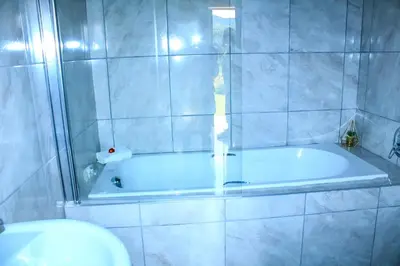 a bathroom with a bath tub and a toilet at Harnham Mountain Lodge in Louis Trichardt