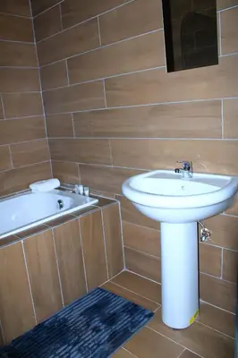 a bathroom with a white sink and a bath tub at Harnham Mountain Lodge in Louis Trichardt