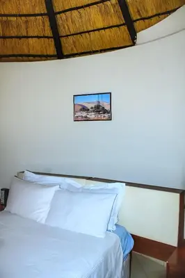a bed with white sheets and a picture on the wall at Harnham Mountain Lodge in Louis Trichardt