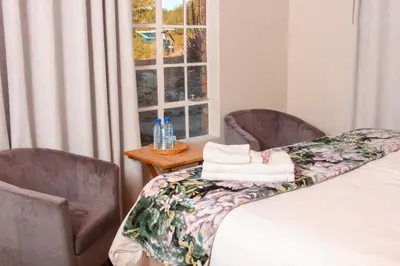 a bedroom with two chairs and a bed and a window at Harnham Mountain Lodge in Louis Trichardt