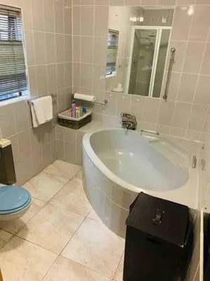 a white bathroom with a tub and a toilet at Serenity Garden Place in Hazyview