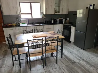 a kitchen with a table and chairs and a refrigerator at Cats Corner in Marloth Park