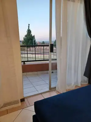 a room with a view of a balcony with white curtains at The cozy 1 bedroom apartment in Midrand