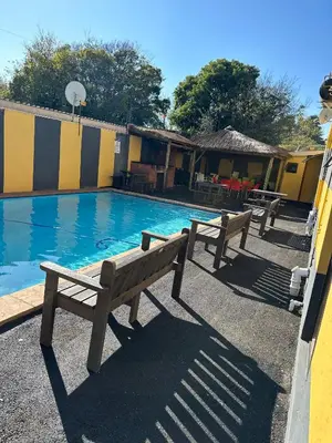 a swimming pool with benches next to a building at Platinum Guesthouse Kempton park in Kempton Park