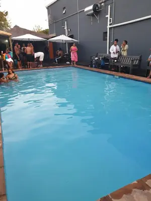 a large swimming pool with people standing around it at Platinum Guesthouse Kempton park in Kempton Park