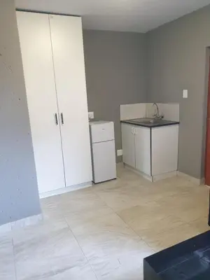 a kitchen with white cabinets and a sink in a room at Platinum Guesthouse Kempton park in Kempton Park