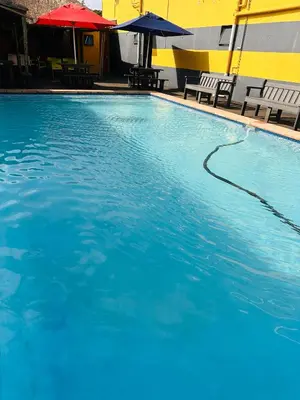 a large pool of blue water with chairs and umbrellas at Platinum Guesthouse Kempton park in Kempton Park