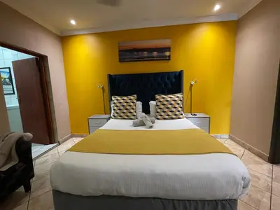 a bedroom with a large bed with yellow walls at The Yacht House in Hartbeespoort