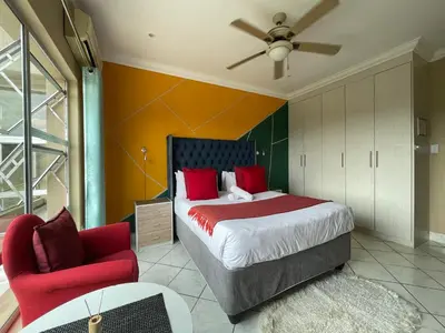 a bedroom with a bed and a red chair at The Yacht House in Hartbeespoort