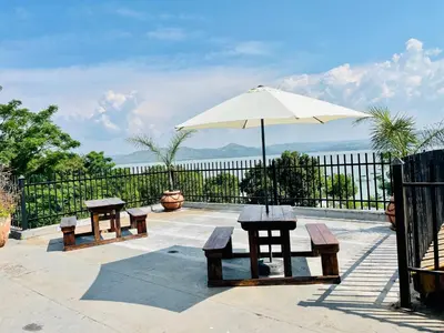 a patio with benches and an umbrella at The Yacht House in Hartbeespoort