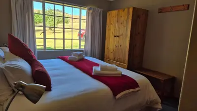 a bedroom with a bed with towels and a window at Apple Blossom Cottage in Dullstroom