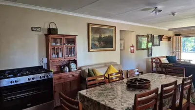 a kitchen and dining room with a table and a stove at Apple Blossom Cottage in Dullstroom